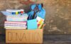 A box of school supplies labeled “donation” sits on a bench.